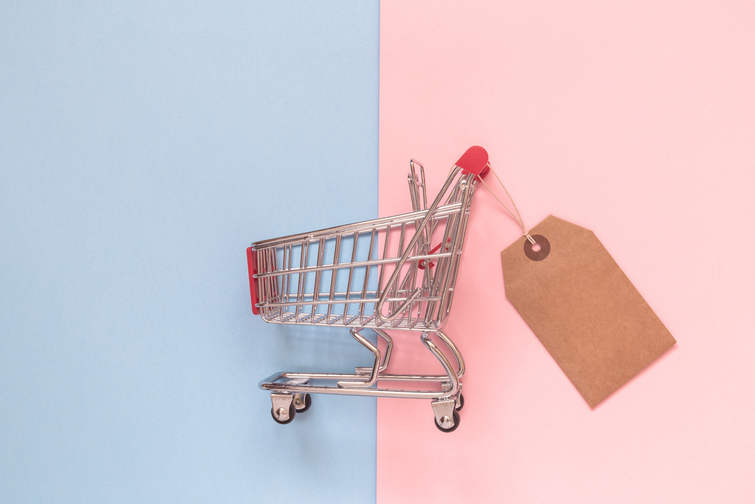 Shopping trolley toy with special offer tag on pastel background minimalistic flat lay concept.
